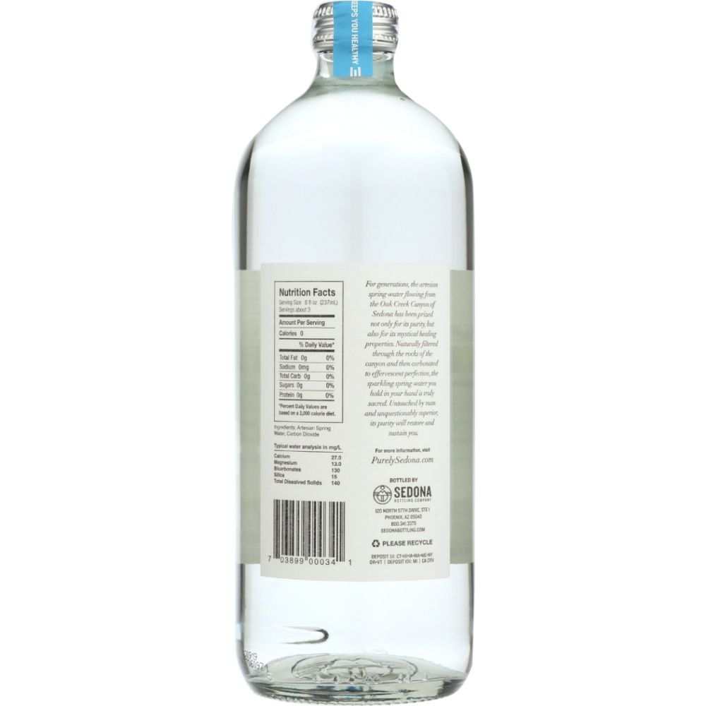 Clear glass bottle of spring water with label showing nutrition facts and ingredient list