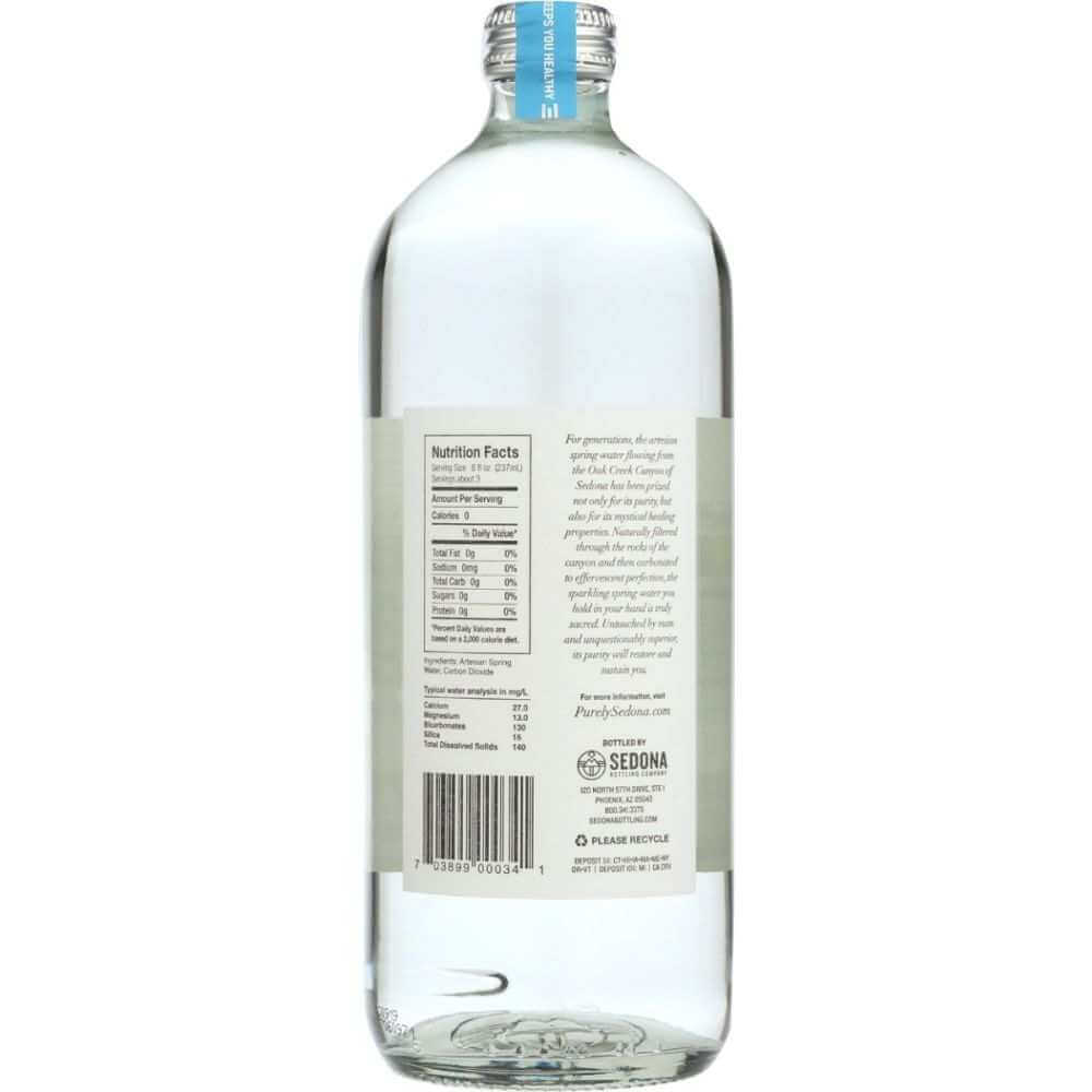 Clear glass bottle of spring water with label showing nutrition facts and ingredient list