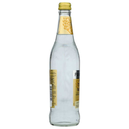 Clear glass bottle of tonic water with yellow label and cap on white background