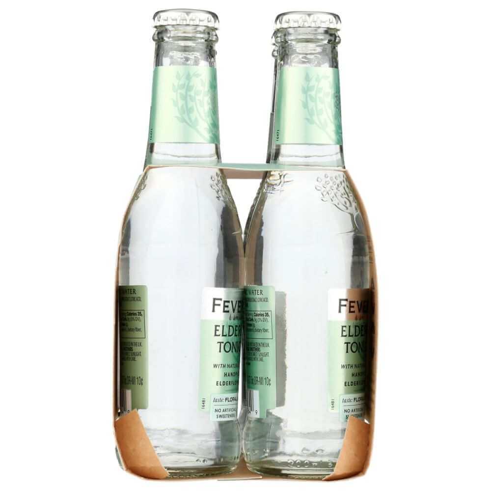 Four glass bottles of elderflower tonic water in cardboard carrier, wellness beverage